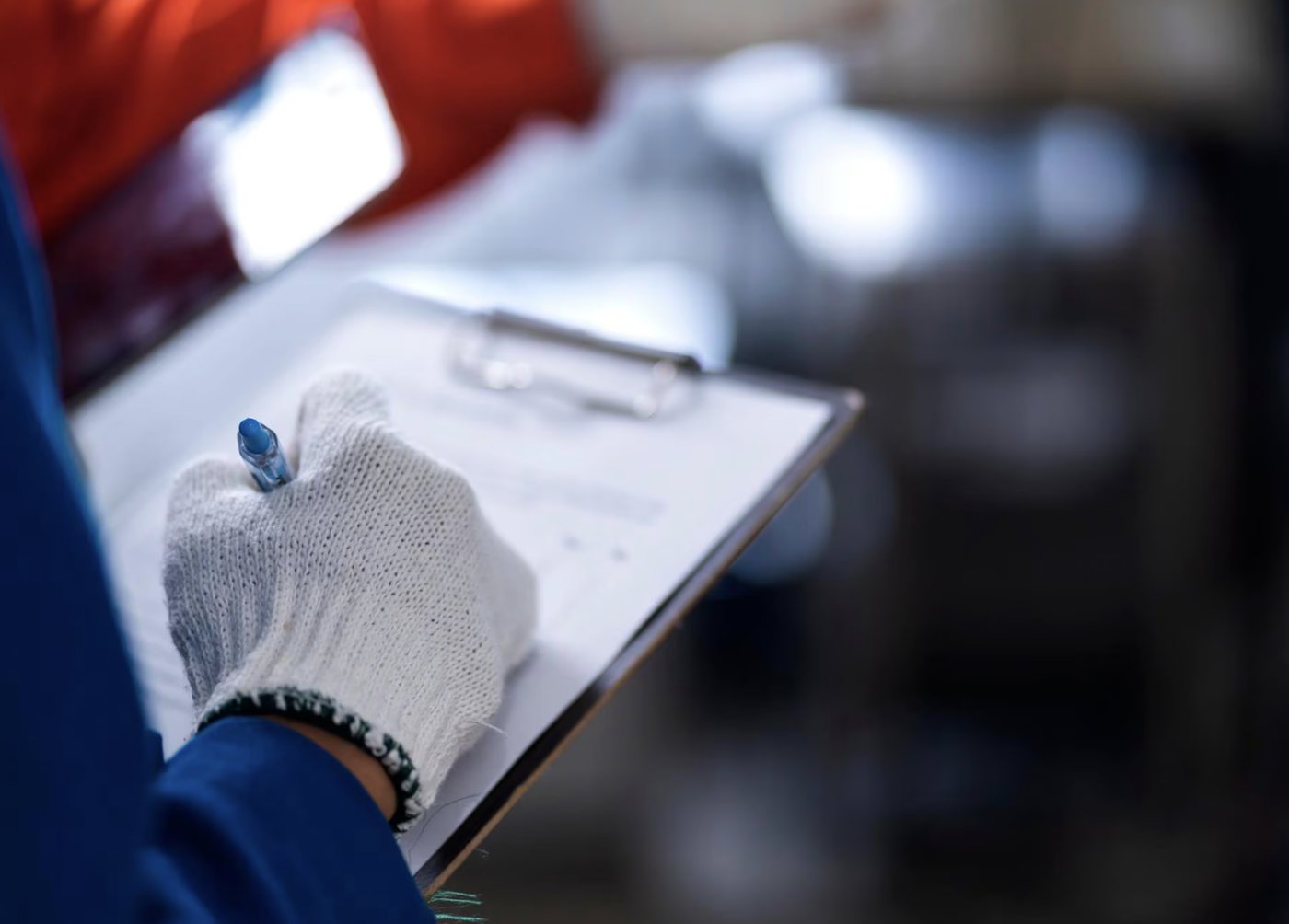 Técnico con guantes anotando una inspección de calidad en una hoja de control
